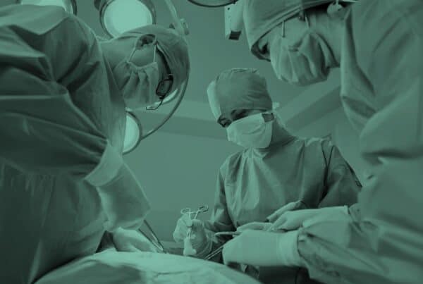 Surgical team in blue medical suits using medical instruments and performing surgery.